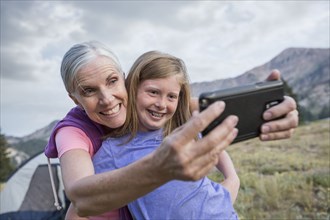 Caucasian grandmother and granddaughter posing for cell phone selfie