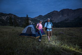 Caucasian couple wearing headlamps at mountain campsite
