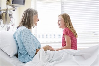 Caucasian granddaughter visiting with grandmother in hospital