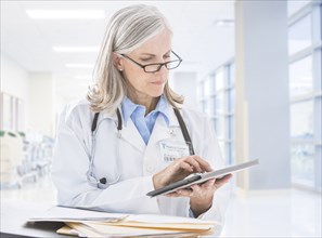 Caucasian doctor reading digital tablet in hospital
