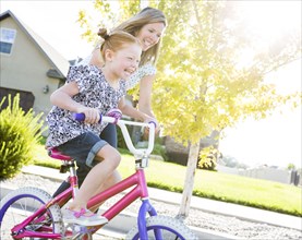Caucasian mother teaching daughter to ride bicycle