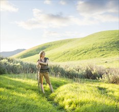 Caucasian woman holding walking stick on hill