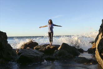 Asian woman standing on rock at beach