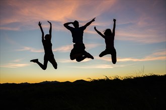 Silhouette of friends jumping for joy at sunset