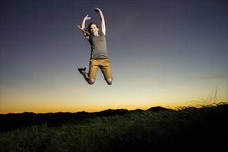 Caucasian woman jumping for joy at sunset