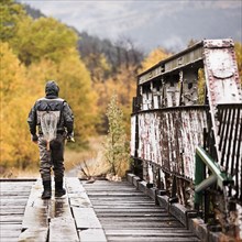 Caucasian man carrying fishing rod on bridge