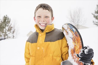 Smiling boy posing with snowboard in winter