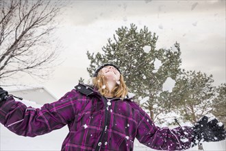 Smiling girl throwing snow in air