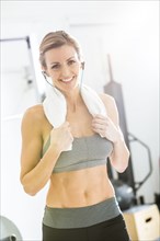 Woman resting with towel around neck in gymnasium