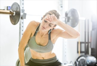 Woman resting in gymnasium wiping sweat from forehead