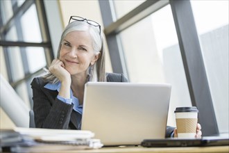 Portrait of smiling Caucasian businesswoman using laptop