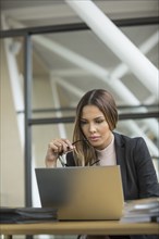 Pensive Mixed Race businesswoman using laptop