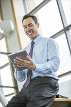 Smiling Mixed Race businessman using digital tablet
