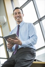 Smiling Mixed Race businessman holding digital tablet