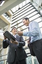 Smiling businessmen using digital tablet in lobby