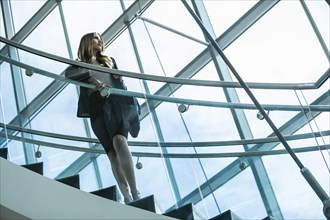 Pensive Mixed Race businesswoman standing on staircase