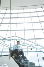 Pensive Mixed Race businessman sitting on staircase