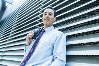 Portrait of smiling Mixed Race businessman leaning on wall