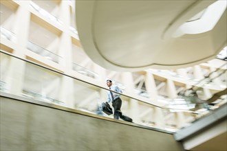 Mixed Race businessman running late in lobby
