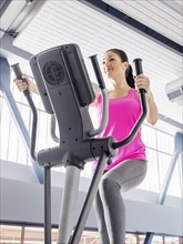 Caucasian woman using elliptical machine in gymnasium