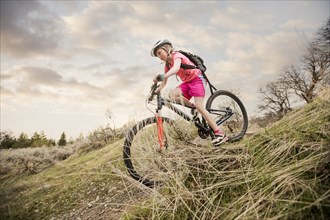 Caucasian girl riding bicycle on hill