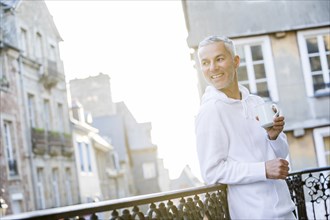 Caucasian man drinking coffee on the balcony in city