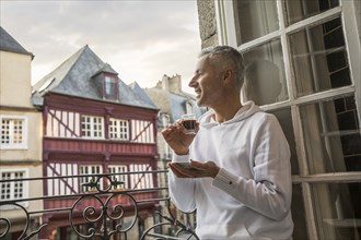 Caucasian man enjoying espresso on balcony in city