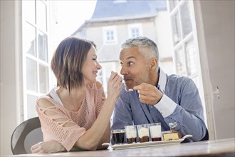 Caucasian woman feeding man dessert in restaurant