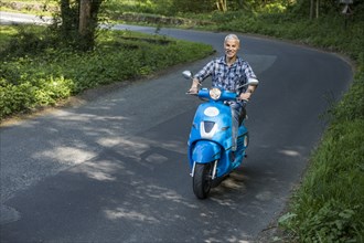 Caucasian man riding blue motor scooter