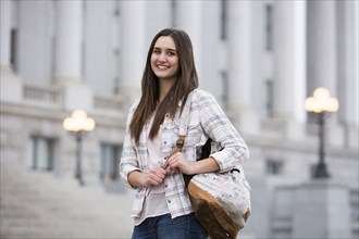 Smiling Caucasian woman carrying backpack at school