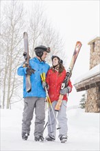 Smiling Caucasian couple carrying skis