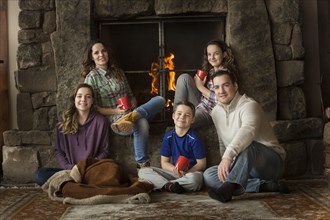 Smiling Caucasian family sitting near fireplace