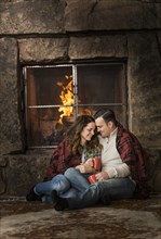 Smiling Caucasian couple cuddling on floor near fireplace