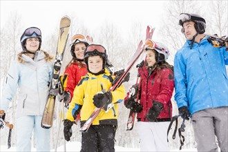 Smiling Caucasian family carrying skis in snow