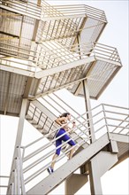 Caucasian woman running on urban staircase