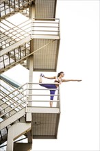 Caucasian woman stretching leg on urban staircase