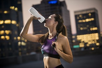 Caucasian woman drinking water on urban rooftop