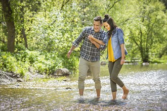 Couple holding hands wading in river