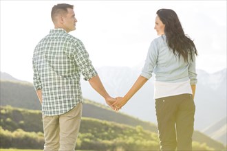 Couple holding hands standing near mountain