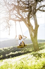 Caucasian woman swinging on tree swing