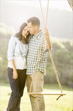 Man hugging woman and holding tree swing
