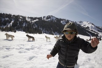 Mixed race boy in snow with dogs and dogsled
