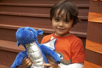 Mixed race boy holding stuffed dragon