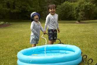 Mixed race children filling inflatable pool