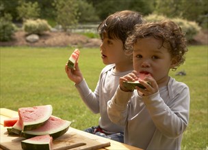 Mixed race children eating watermelon