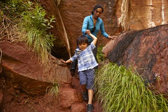 Mother helping son climb down rocks