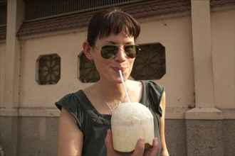 Mixed race woman drinking from coconut