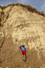 Mixed race boy climbing dirt cliff