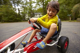 Mixed race boy riding toy car
