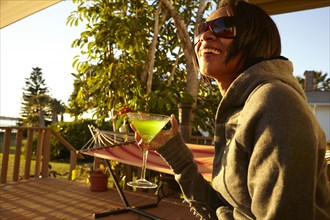 Mixed race woman having cocktail on porch